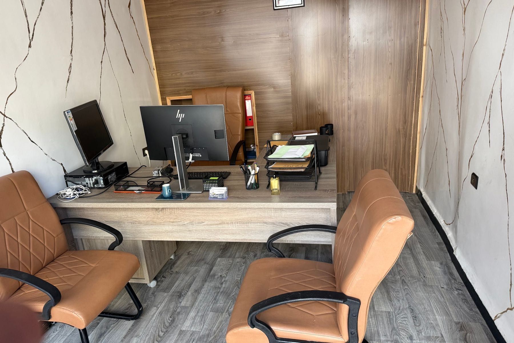 Bureau de l’agence : poste de travail, deux fauteuils en cuir, murs effet marbre